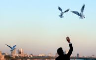 A man feeds birds along the al-Jadriyah bridge in the centre of Baghdad at sunset, on February 18, 2023. (Photo by Murtadha RIDHA / AFP) (Photo by MURTADHA RIDHA/AFP via Getty Images)