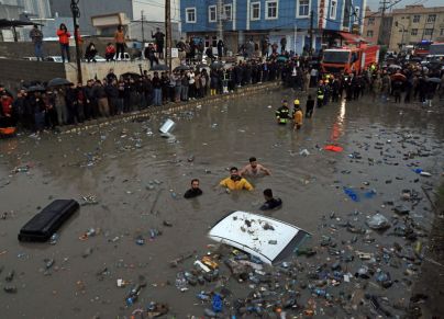 ERBIL, IRAQ - FEBRUARY 15: Firefighters and civilians try to rescue a vehicle stuck in the flooded area after heavy rains cause flash floods in Erbil, Iraq on February 15, 2024. (Photo by Ahsan Mohammed Ahmed Ahmed/Anadolu via Getty Images)