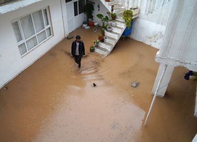 TOPSHOT - A man walks in a flooded courtyard following heavy rains in Dohuk in Iraq's northern autonomous Kurdistan region on March 19, 2024. (Photo by Ismael ADNAN / AFP) (Photo by ISMAEL ADNAN/AFP via Getty Images)