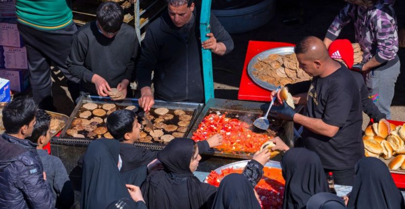 Iraqi Shiite Muslim pilgrims receive food from volunteers as they march from the centre of Baghdad toward the shrine of the 8th-century Imam Musa al-Kadhim in the Kadhimiya district, north of the capital, on February 15, 2023. - Pilgrims from various Iraqi provinces undertake a march on foot to reach the shrine in the capital to commemorate the eighth century death of Imam Musa, who is believed to have been poisoned by agents of the then ruler Harun al-Rashid. (Photo by Murtadha RIDHA / AFP) / The erroneous